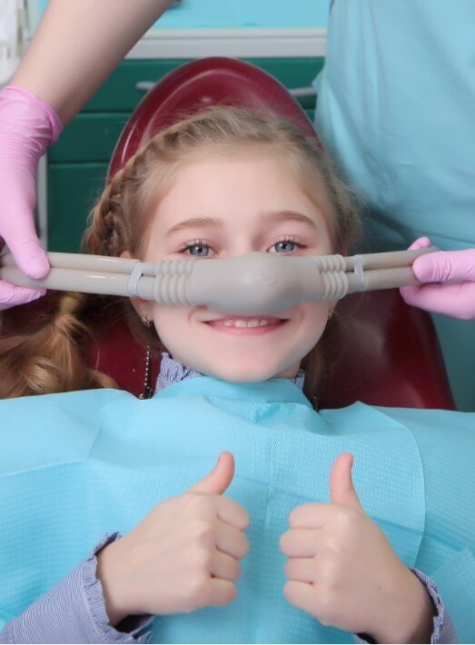 Young girl giving thumbs up while receiving nitrous oxide sedation dentistry in Los Angeles