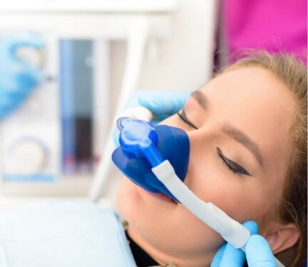 Young woman with eyes closed in dental chair with nitrous oxide sedation mask on her face