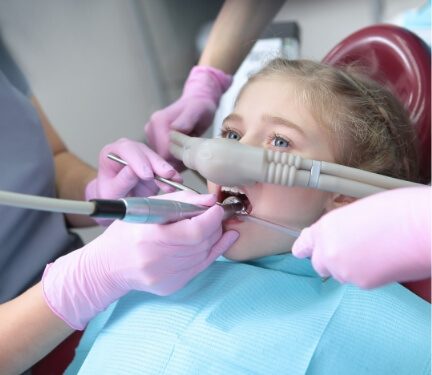Young girl receiving dental procedure while wearing sedation dentistry mask