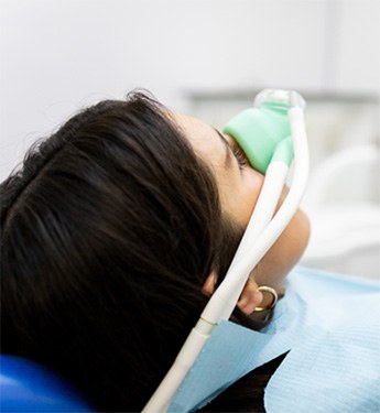 Patient sitting in treatment chair with nasal mask