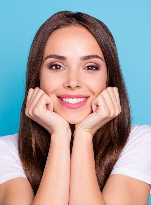 Woman grinning against blue background after smile makeover in Los Angeles