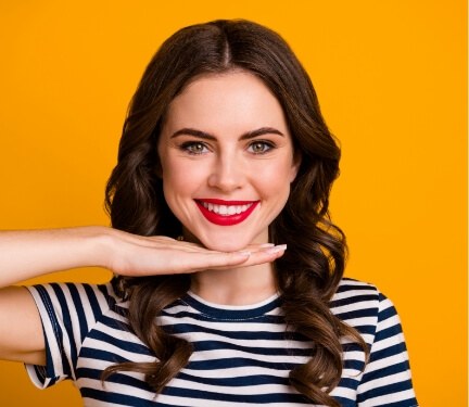 Woman showing off her smile in front of yellow background