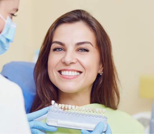 Young woman gesturing to row of dental veneers next to her smile