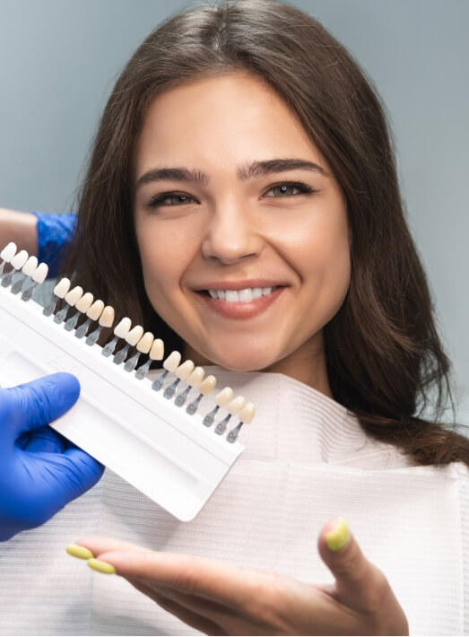 Young woman gesturing to row of dental veneers next to her smile
