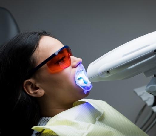 Woman getting teeth whitening in dental office