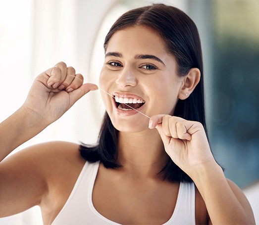 Woman smiling while flossing her teeth