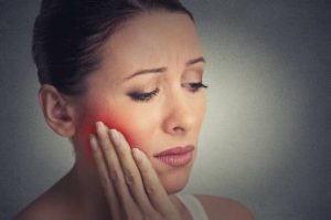 Woman holds her face in pain