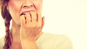 woman biting on four fingernails