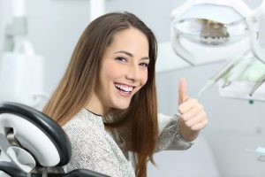 woman in dental chair thumb up