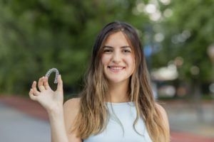 Woman undergoing Invisalign treatment holding aligners