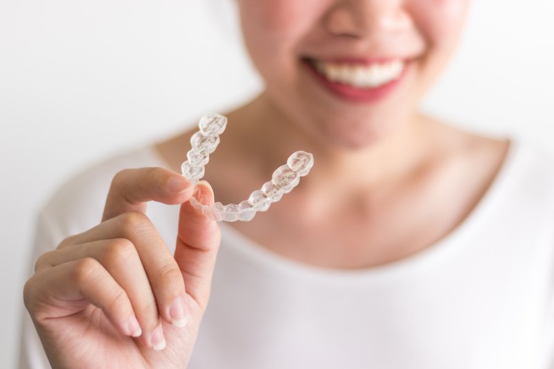 woman smiling with aligner in her hand