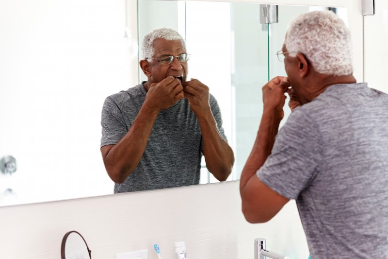 Senior man flossing in the mirror