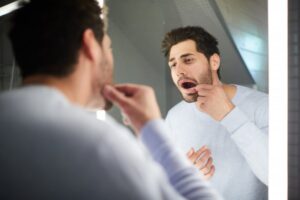 Man looking into his mouth with a mirror