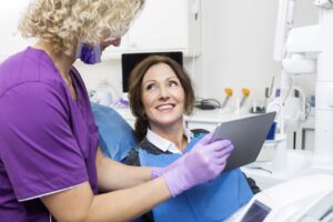 Dentist showing smiling patient info on a tablet.